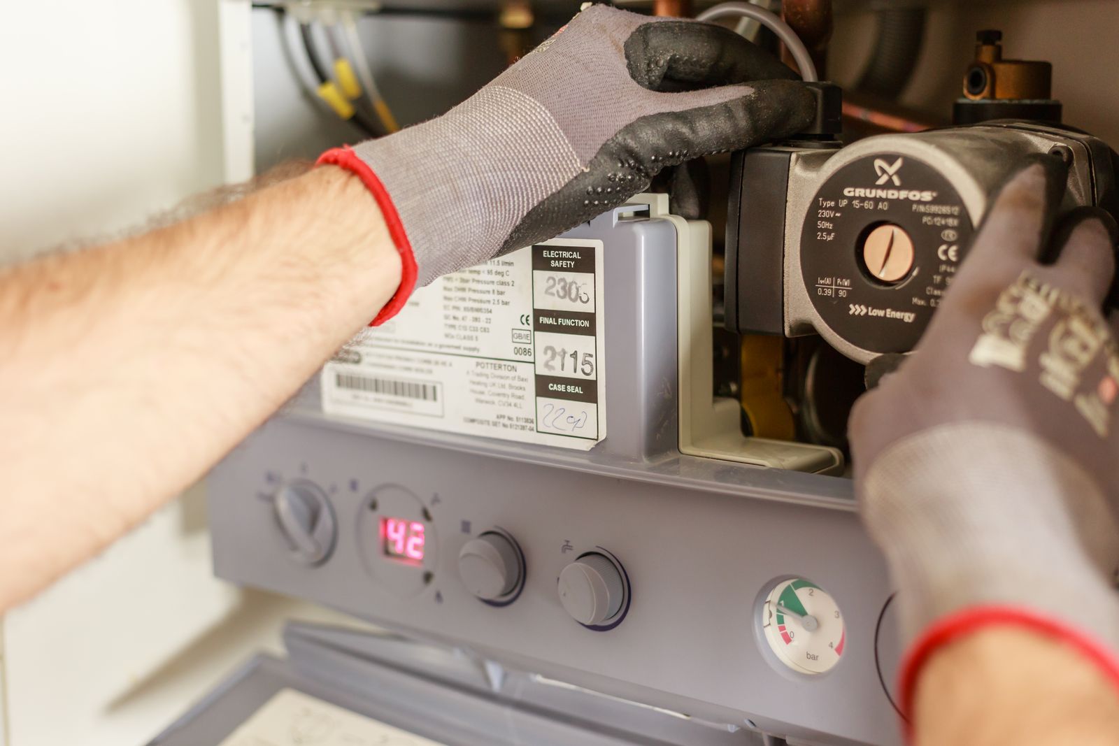 Technician servicing the internal components of a home heating system with gloved hands