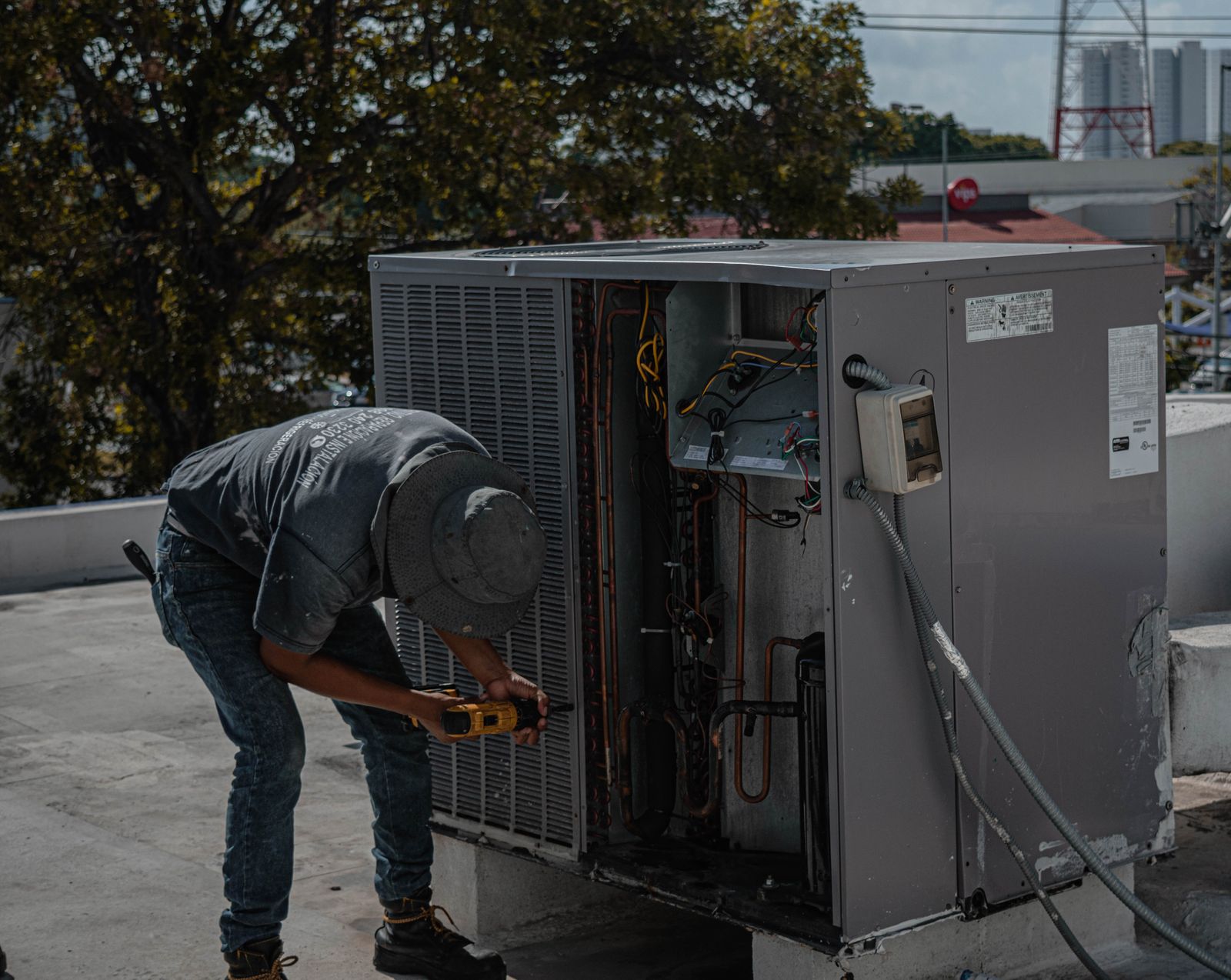 Technician repairing an outdoor air conditioning unit with the access panel open