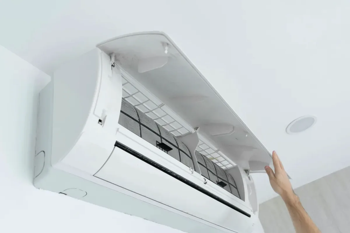 Hand opening the cover of a wall-mounted ductless air conditioner